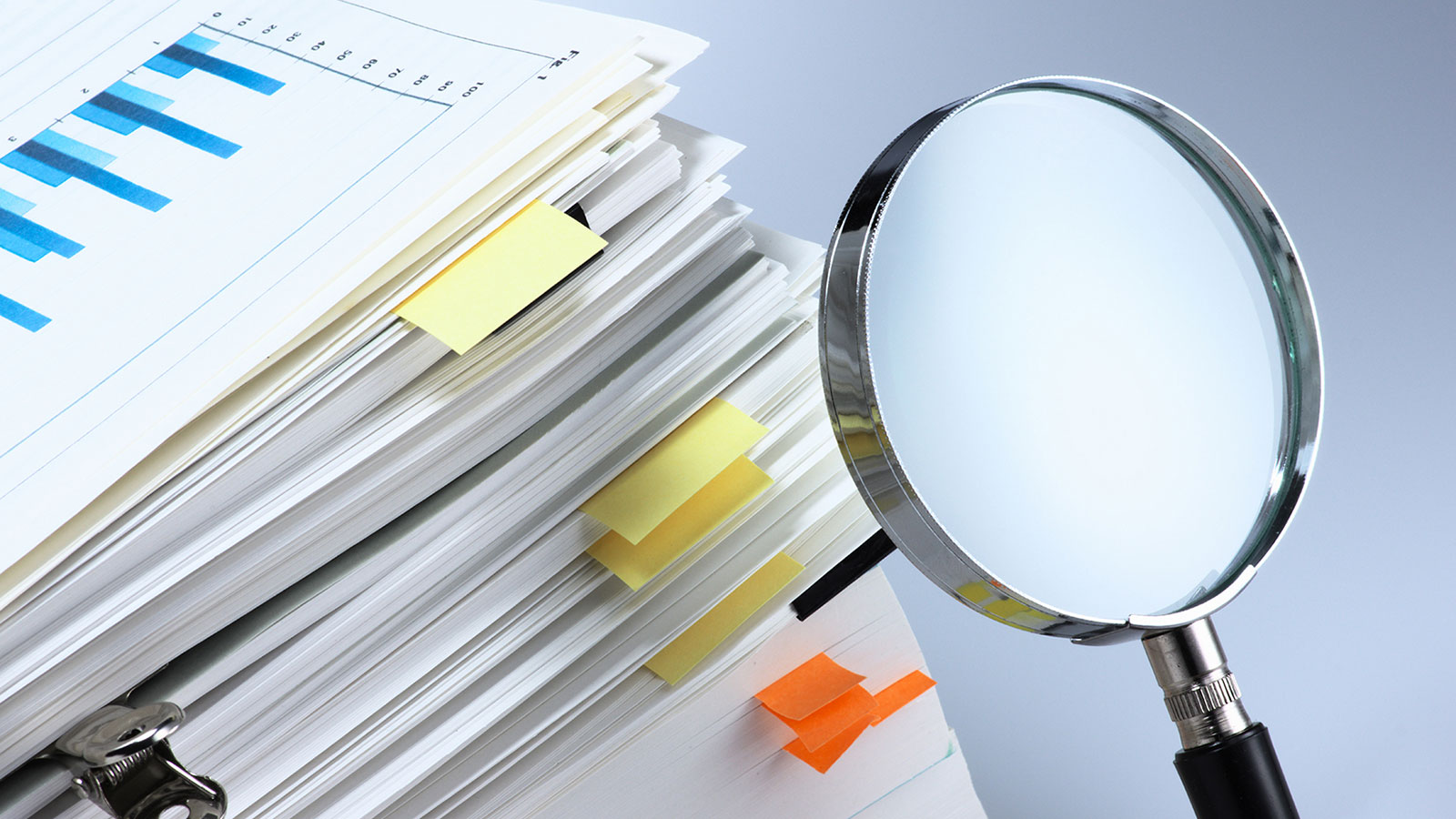 Stack of papers and magnifying glass