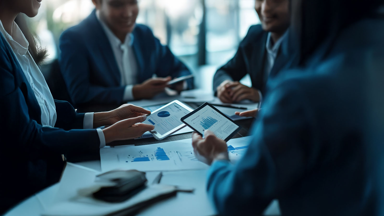 A private equity investment team conducting a due diligence meeting, digital tablets and financial reports on the table, diverse