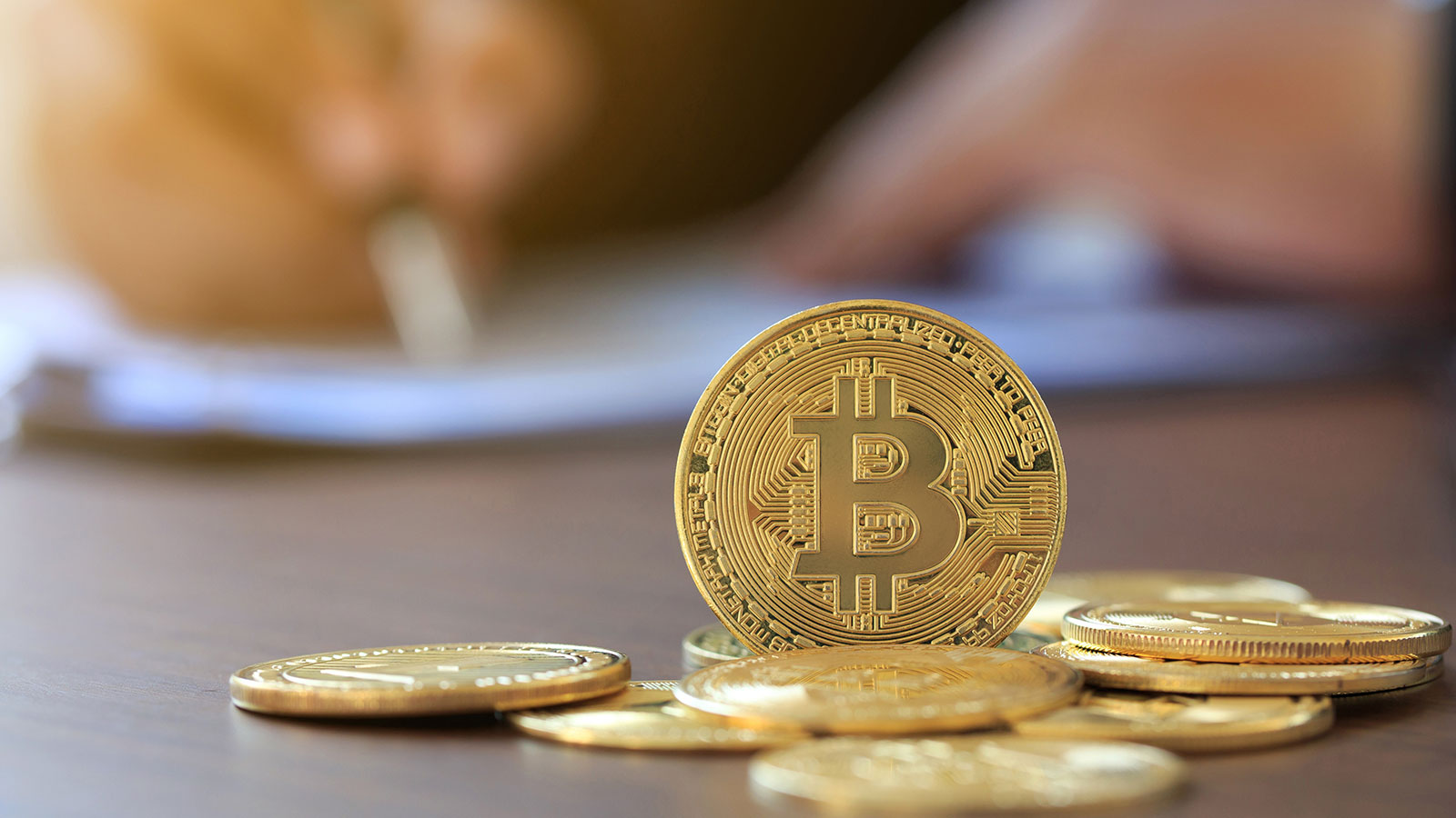 Bitcoin on wooden table and man signing individual income tax return form 1040