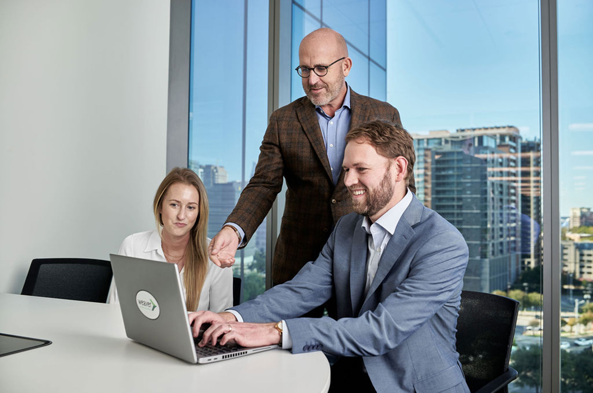 Weaver employees gathered and reviewing documents on a laptop