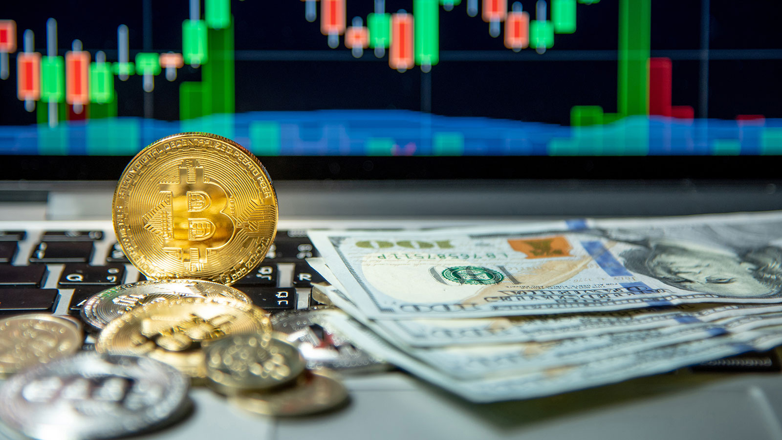 Studio shot of bitcoin gold silver coins and dollar bank note on laptop